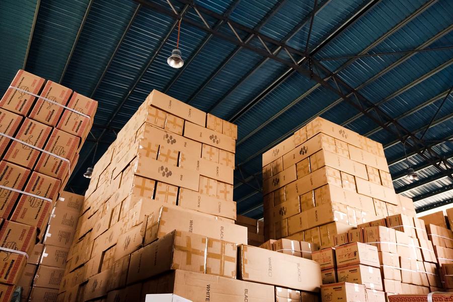 Stacked cartons in a warehouse holding bulk orders ahead of a staged rollout