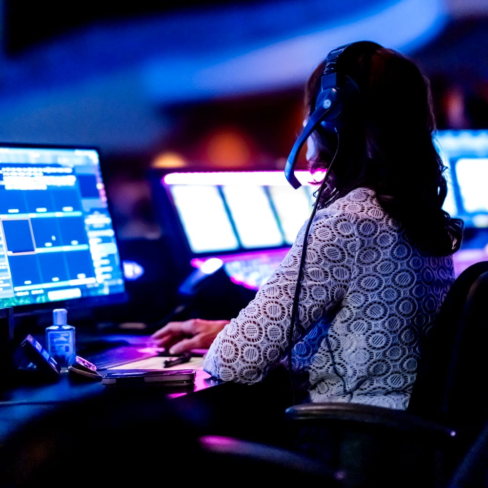 Operator with a headset watching monitoring screens in a network operations centre